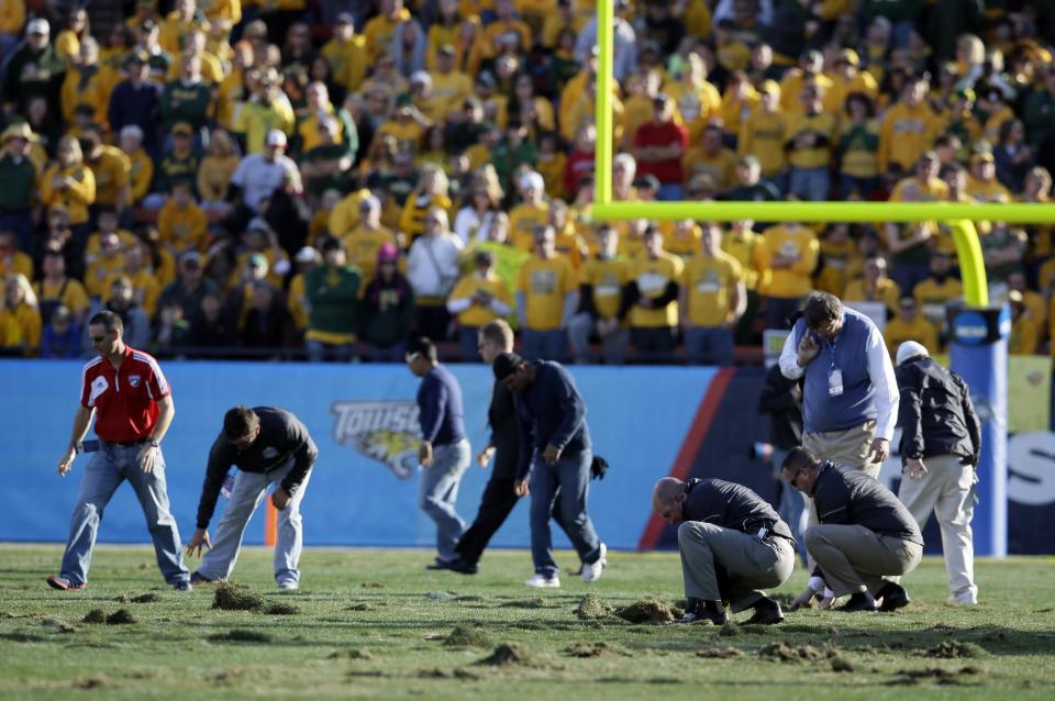 Stadium officials and volunteers replaces chunks of turf on the field in the second half of the FCS championship NCAA college football game between North Dakota State and Towson, Saturday, Jan. 4, 2014, in Frisco, Texas. During each timeout, groups of workers and volunteers patted down chunks of turf that were coming up during play. NDSU won 35-7. (AP Photo/Tony Gutierrez)