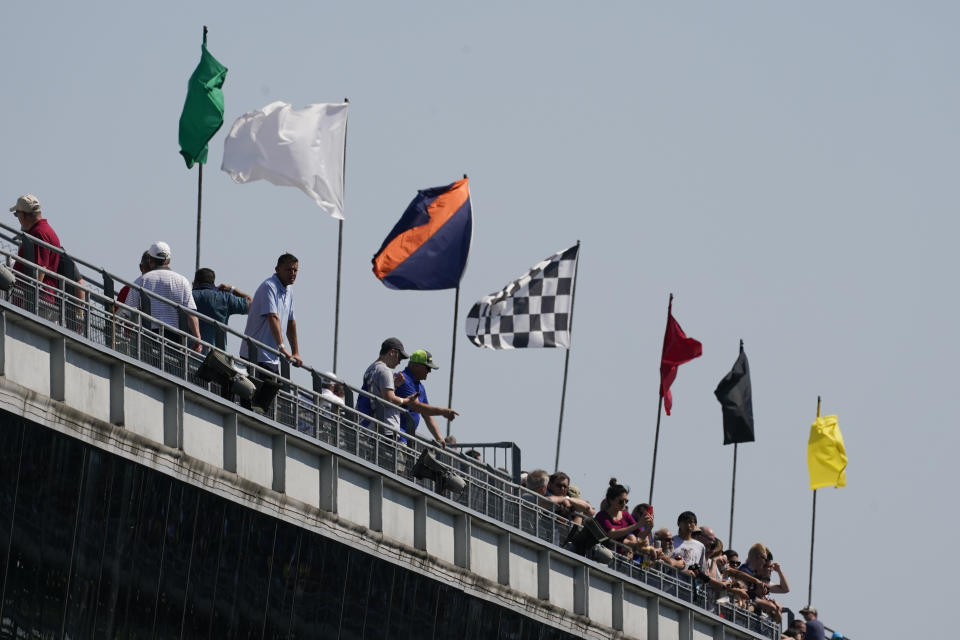 Fans look on as the flags blow in the wind during practice for the Indianapolis 500 auto race at Indianapolis Motor Speedway, Friday, May 20, 2022, in Indianapolis. (AP Photo/Darron Cummings)