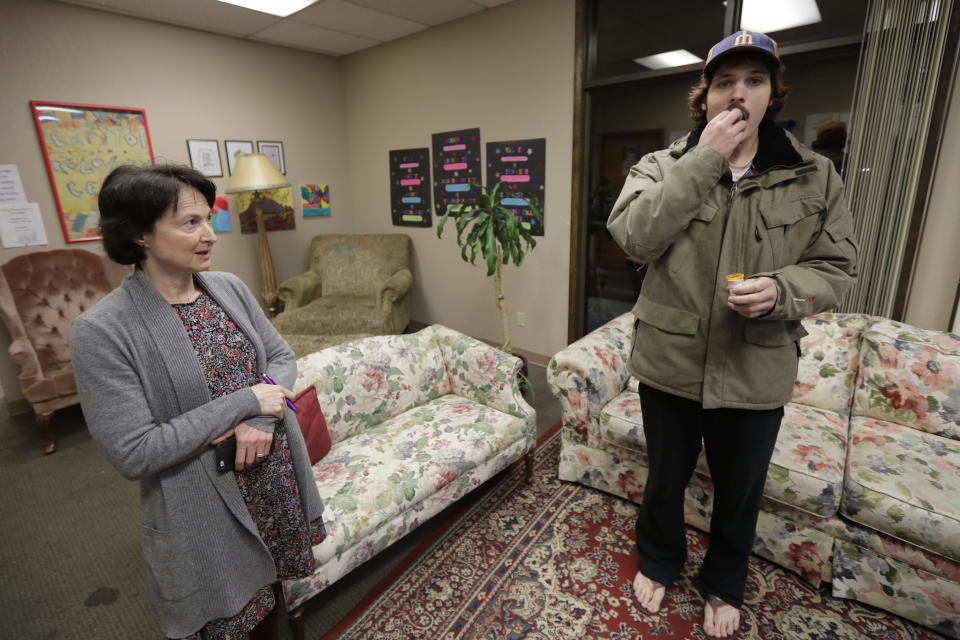 CORRECTS TO CAPITAL, NOT CAPITOL- In this Nov. 14, 2019 photo, Jon Combes, right, takes a dose of buprenorphine, a medicine that prevents withdrawal sickness in people trying to stop using opiates, as he stands near Dr. Lucinda Grande, left, medical director of the Olympia Bupe Clinic at the Capital Recovery Center, in Olympia, Wash., which helps people addicted to heroin and other opiates get prescriptions for buprenorphine. At the clinic, Grande is working to spread a philosophy called "medication first," which scraps requirements for counseling, abstinence or even a commitment to recovery in the battle against opioid addiction. (AP Photo/Ted S. Warren)