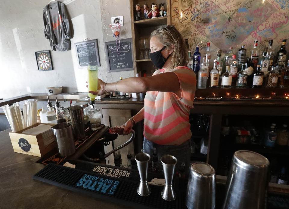 Danielle Savin, co-owner of a bar called Bob's Your Uncle, pours a drink, Tuesday, June 30, 2020, at the bar in Miami Beach, Fla. Savin owns two bars that were forced to shut down for months in both New York and Miami Beach. When the pandemic first hit and New York was the country's epicenter she feared for that business, but months later the two states have flip-flopped. (AP Photo/Wilfredo Lee)