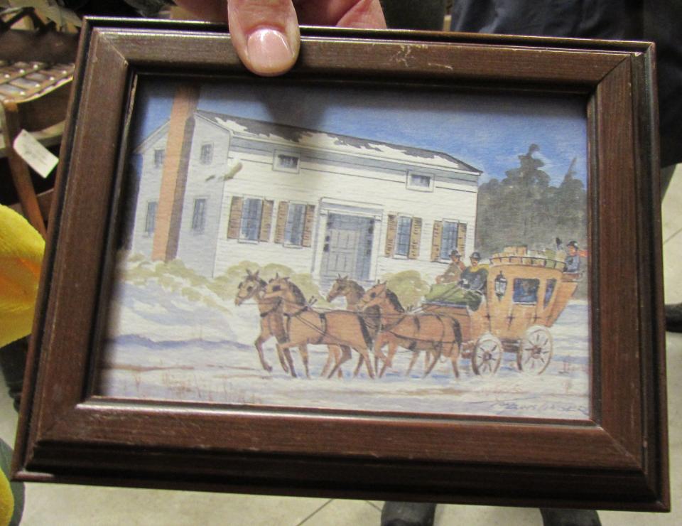 Tammie Menke, the vice president of the Stow Historical Society, holds a framed painting of the Heritage House. The building had been a stagecoach stop located near the intersection of Graham and Fishcreek roads.