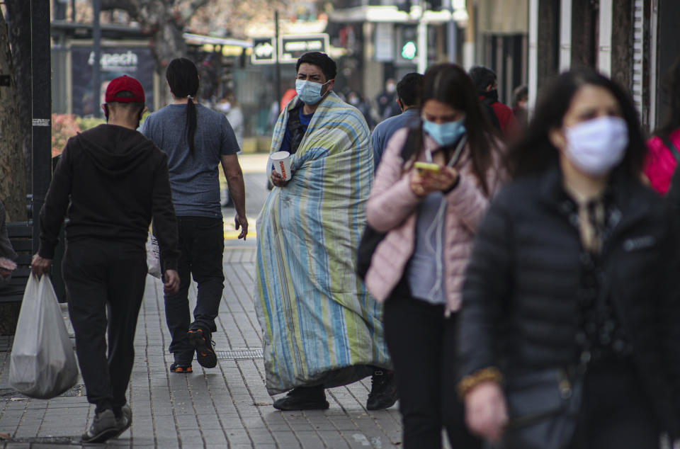 Un hombre sin hogar que usa una mascarilla para prevenir el nuevo coronavirus pide monedas a peatones en una calle de Santiago, Chile, el lunes 3 de agosto de 2020. (AP Foto/Esteban Felix)