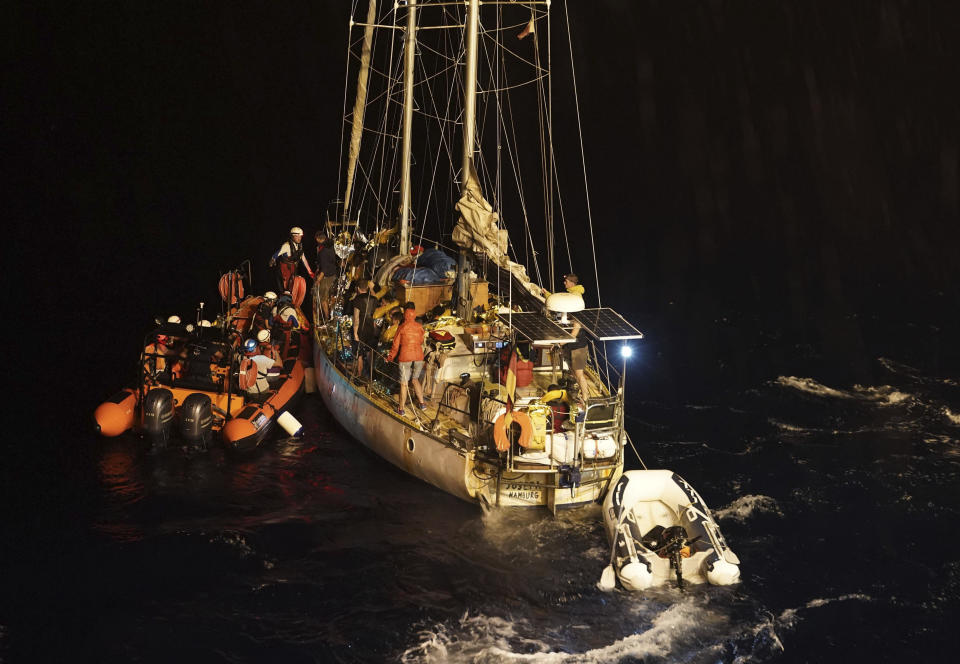 A member of the SOS Mediterranee search and rescue team speaks to a member of the German group Resqship before migrants rescued by the Josefa are to be onto a dinghy to be taken onto the humanitarian ship Ocean Viking, in the Mediterranean Sea, late Monday, Sept. 9, 2019. Thirty-four migrants including women and the small child who were rescued by the German sailboat have been successfully taken aboard the humanitarian ship in international waters north of Libya despite a thunderstorm. (AP Photo/Renata Brito)