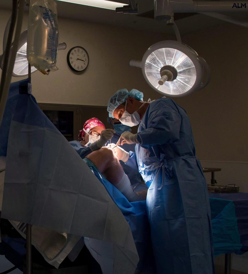 A doctor operates on a patient's knee