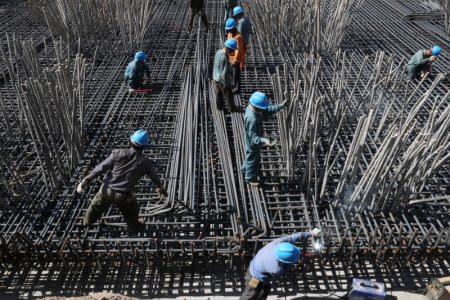 Workers are seen amid steel bars at a construction site of a highway in Zhaotong, Yunnan province, China April 20, 2018. Picture taken April 20, 2018. REUTERS/Stringer