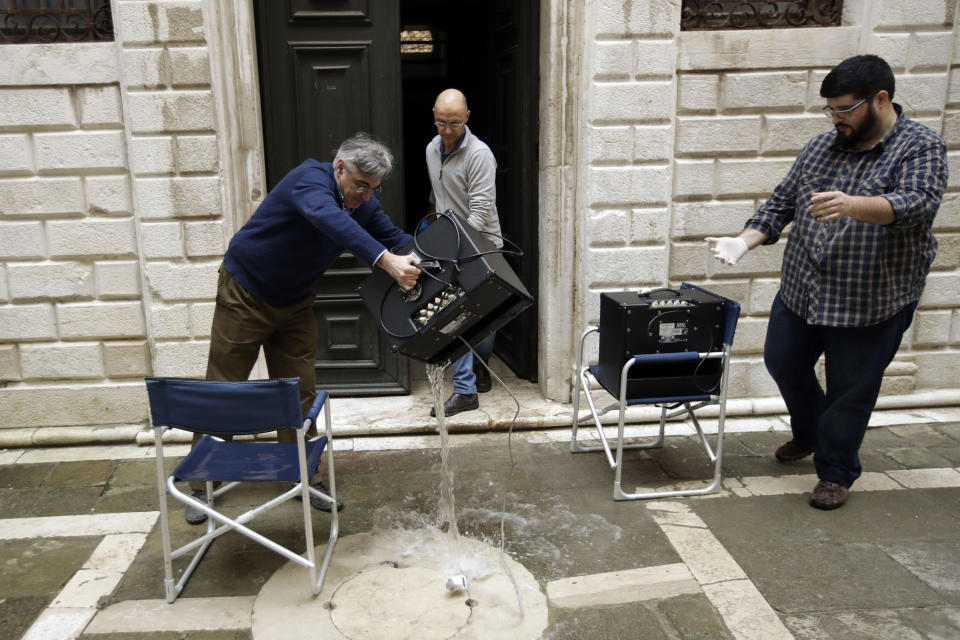 A man empties electronic equipment from water in Venice, Italy, Saturday, Nov. 16, 2019. High tidal waters returned to Venice on Saturday, four days after the city experienced its worst flooding in 50 years. (AP Photo/Luca Bruno)