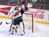 Florida Panthers' Colin White (6) and Winnipeg Jets goaltender Connor Hellebuyck (37) reach for the puck during the third period of an NHL hockey game Tuesday, Dec. 6, 2022, in Winnipeg, Manitoba. (Fred Greenslade/The Canadian Press via AP)