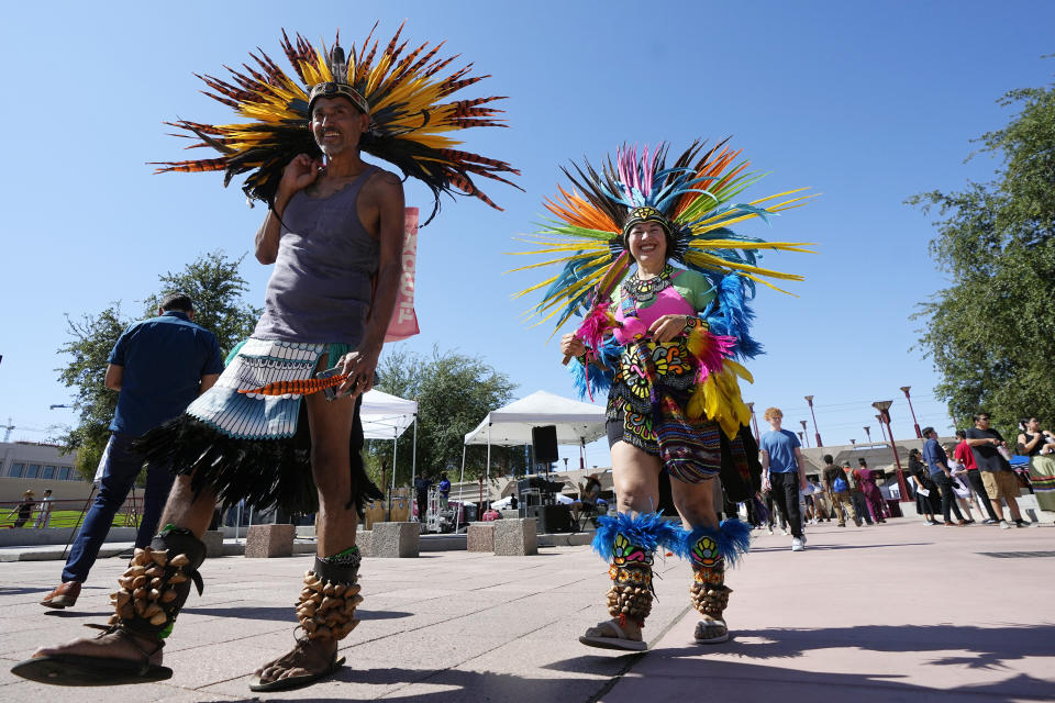 People wearing traditional Aztec dance clothing walk through an Indigenous Peoples Day festival, Monday, Oct. 9, 2023, in Phoenix. (AP Photo/Ross D. Franklin)