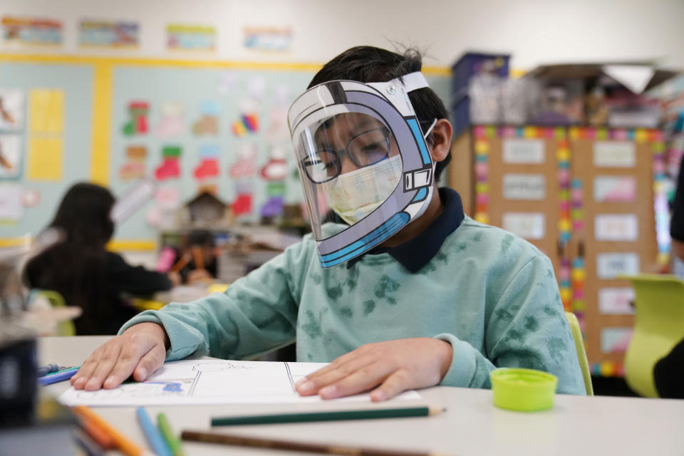 FILE - A student wears a mask and face shield in a 4th grade class amid the COVID-19 pandemic at Washington Elementary School on Jan. 12, 2022, in Lynwood, Calif. As a new school year approaches, COVID-19 infections are again on the rise, fueled by highly transmissible variants, filling families with dread. They fear the return of a pandemic scourge: outbreaks that sideline large numbers of teachers, close school buildings and force students back into remote learning. (AP Photo/Marcio Jose Sanchez, File)