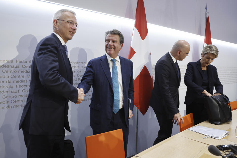 Axel Lehmann, Chairman Credit Suisse, left, and Colm Kelleher, Chairman UBS, shake hands beside Swiss Federal President Alain Berset and Swiss Finance Minister Karin Keller-Sutter, at the end of a press conference in Bern, Switzerland, Sunday March 19, 2023. Banking giant UBS is acquiring its smaller rival Credit Suisse in an effort to avoid further market-shaking turmoil in global banking, Swiss President Alain Berset announced on Sunday. (Peter Klaunzer/Keystone via AP)