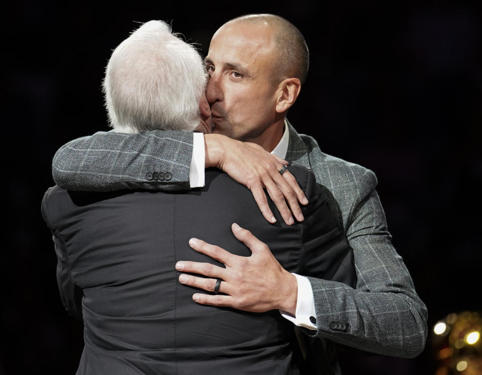 Former San Antonio Spurs guard Manu Ginobili, right, kisses Spurs coach Gregg Popovich on the cheek during Ginobili's retirement ceremony after the team's NBA basketball game against the Cleveland Cavaliers, Thursday, March 28, 2019, in San Antonio. San Antonio won 116-110. (AP Photo/Darren Abate)