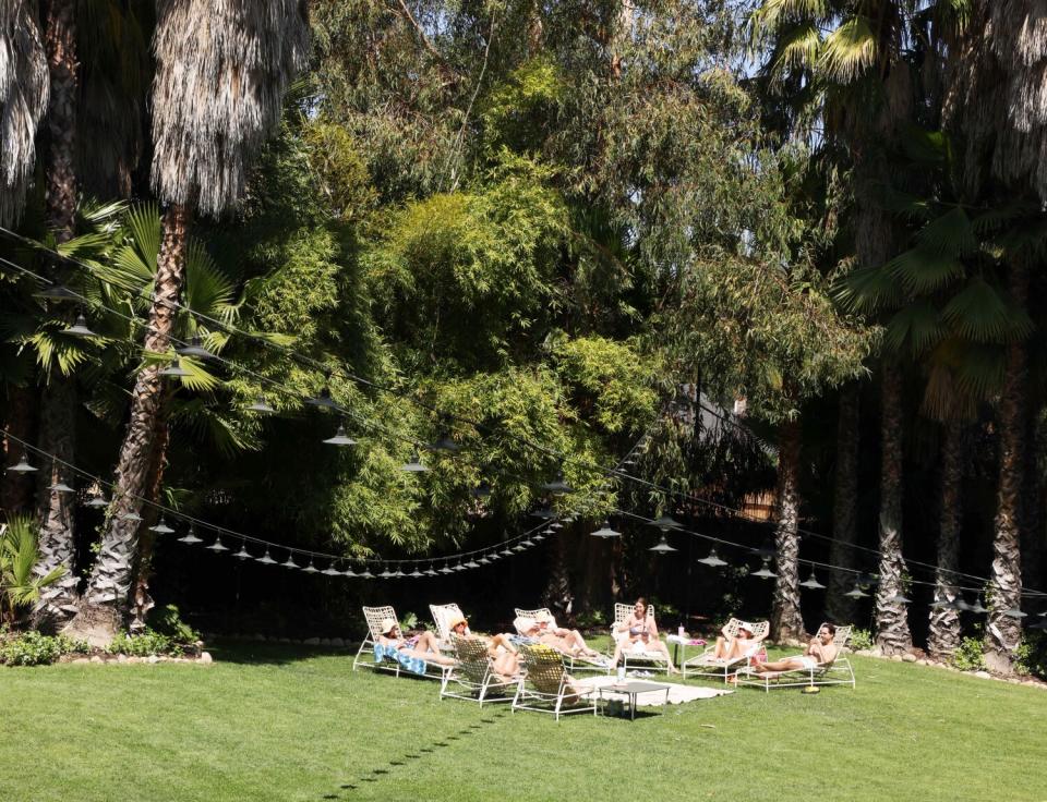 People lounging on chairs on the grass outside the Capri Hotel