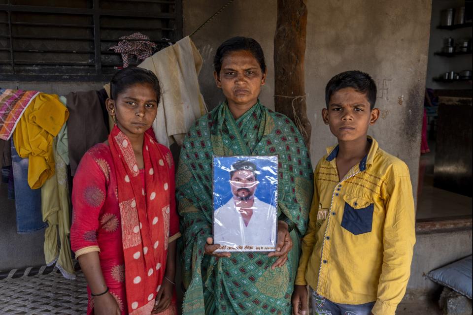 Shobha Londhe, center, holds an image of her husband, farmer Tatya Londe, who killed himself, while posing with her kids Datta Londe, right, and Anjali Londe, left, at their house in Talegaon village, Beed district, India, Friday, May 3, 2024. Londhe is one of India's 120 million farmers who share fast-shrinking water resources as groundwater is pumped out faster than rain can replenish it. “He was struggling because we were always in debt,” she said. (AP Photo/Rafiq Maqbool)