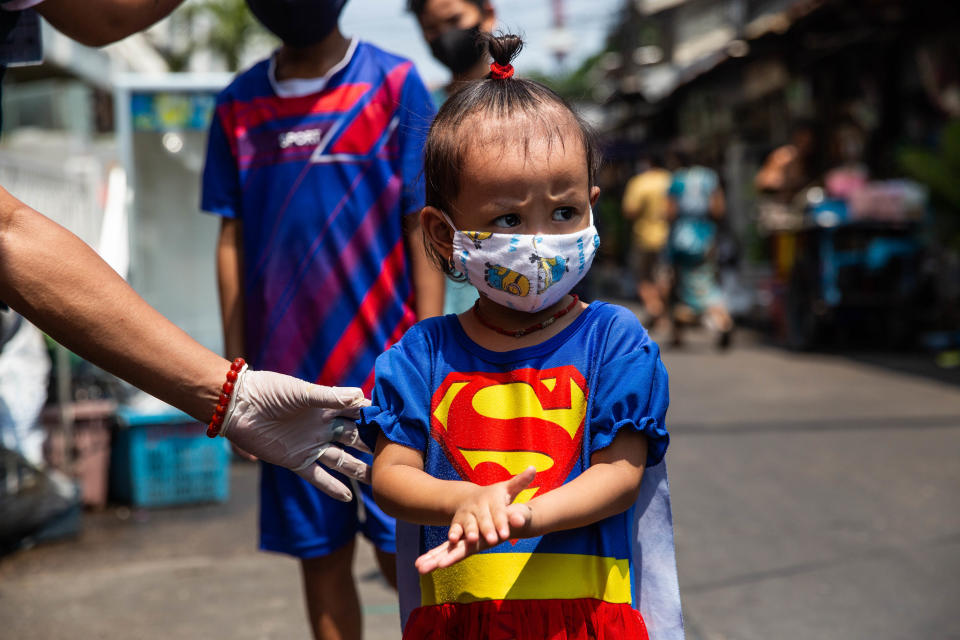 BANGKOK, THAILAND - APRIL 22:  A little Thai girl in the Bonkai community in Bangkok's Pathumwan district uses hand sanitizer as she stands in a social distancing queue to recieve food, water and face mask from the Poh Tek Tung Foundation on April 22, 2020 in Bangkok, Thailand.  The Poh Tek Tung Foundation, which primarily serves as a rescue organization is doing daily donations to poorer communities throughout Bangkok during the lockdown imposed by the Thai government as an effort to stop the spread of Covid-19. Due to the economic impact of the coronavirus pandemic, many community members have lost work and jobs due to the shutdown of businesses throughout the city and rely on donations for daily food. Thailand currently has 2,826 confirmed cases of Covid-19. (Photo by Lauren DeCicca/Getty Images)