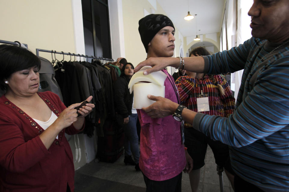 In this Feb. 5, 2013 photo, Eric Salas holds still as he is prepared to model clothing at the Bionic Fashion show, backstage at the Metropolitan Cultural Center in Quito, Ecuador. Salas, from Venezuela, is a cancer survivor whose right arm was amputated due to his illness. He joined 15 other models from Argentina, Brazil, Bolivia, Costa Rica, Colombia and Ecuador to model creations by Ecuadorian designers at an event organized by the Youth Against Cancer Foundation which aimed to break stereotypes and social barriers for the young cancer survivors. (AP Photo/Dolores Ochoa)