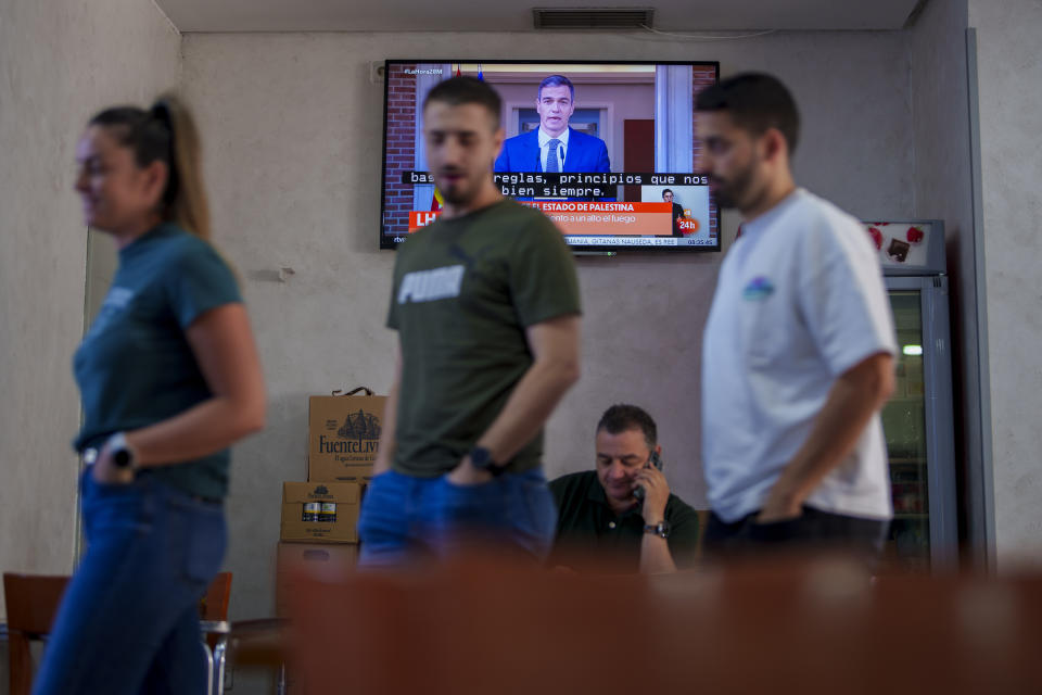 Clientes de un bar pasan por delante de un televisor que emite una comparecencia en vivo del presidente del gobierno de España, Pedro Sánchez, en Rivas Vaciamadrid, Madrid, el 28 de mayo de 2024. (AP Foto/Manu Fernández)