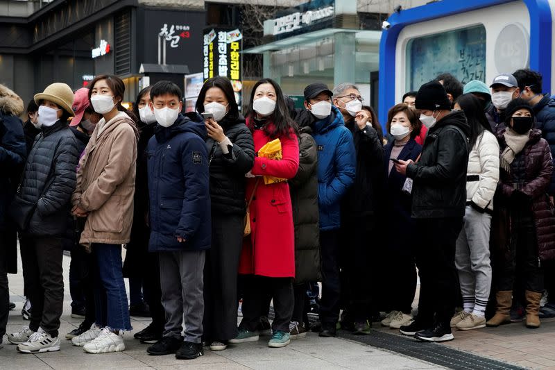 Personas con máscaras después del brote de coronavirus esperan en una fila para comprar máscaras frente a unos grandes almacenes en Seúl, Corea del Sur