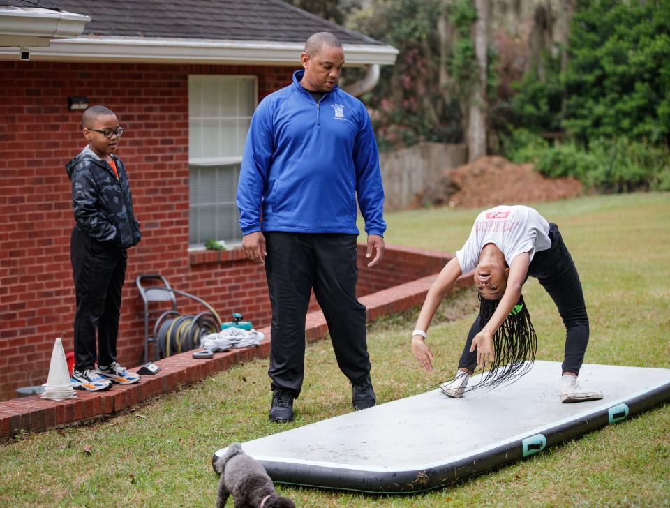 Tallahassee Police Department Sgt. Damon Miller and his son Damon, 8, watch Miller's daughter Bailey, 11, do a back walkover in their backyard Thursday, March 17, 2022.