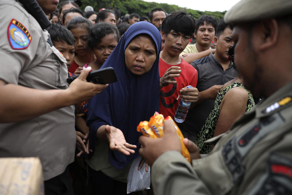 People queue up to receive food at an aid distribution point for those affected by the floods in Jakarta, Indonesia, Saturday, Jan. 4, 2020. Monsoon rains and rising rivers submerged parts of greater Jakarta and caused landslides in Bogor and Depok districts on the city's outskirts as well as in neighboring Lebak, which buried a number of people. (AP Photo/Dita Alangkara)