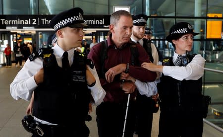 Police officers detain environmental activist James Brown at Heathrow Terminal 2, after climate change protesters tried to launch drones within the airport's exclusion zone, in London