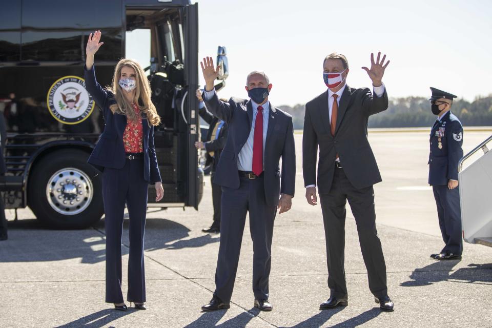 Vice President Mike Pence, center, Senator Kelly Loeffler, left, and Senator David Perdue, right, wave at individuals at Dobbins Air Reserve Base in Marietta, Ga., Friday, Nov. 20, 2020. Pence arrived on Friday to support Loeffler and Perdue, who are both facing a run-off election in January. (Alyssa Pointer /Atlanta Journal-Constitution via AP)