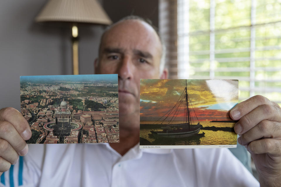 FILE - In this July 26, 2019, file photo, James Grein poses at home in Sterling, Va., with postcards from Florida and the Vatican sent to him as a boy by now-defrocked Cardinal Theodore McCarrick. Grein claims in a lawsuit in New Jersey that he told Pope John Paul II in 1988 about being sexually abused as a child by McCarrick but that the Vatican did nothing. (AP Photo/Manuel Balce Ceneta, File)