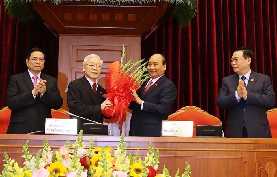 Vietnam Communist party General Secretary Nguyen Phu Trong, center left, is presented with a bouquet by Prime Minister Nguyen Xuan Phuc, center right, in Hanoi, Vietnam, Sunday, Jan. 31, 2021. Vietnam Communist Party has re-elected Nguyen Phu Trong for another term as the party's General Secretary, the country de-facto top leader. (Le Tri Dung/VNA via AP)