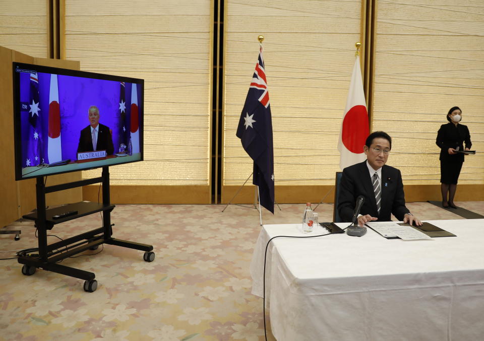 Japan's Prime Minister Fumio Kishida, front right, and Australia's Prime Minister Scott Morrison, left and seen on screen, attend a virtual summit to sign the Reciprocal Access Agreement, at Kishida's official residence in Tokyo, Japan Thursday, Jan. 6, 2022. The leaders of Japan and Australia signed a “landmark” defense agreement Thursday that allows closer cooperation between their militaries and stands as a rebuke to China's growing assertiveness in the Indo-Pacific region. (Issei Kato/Pool Photo via AP)