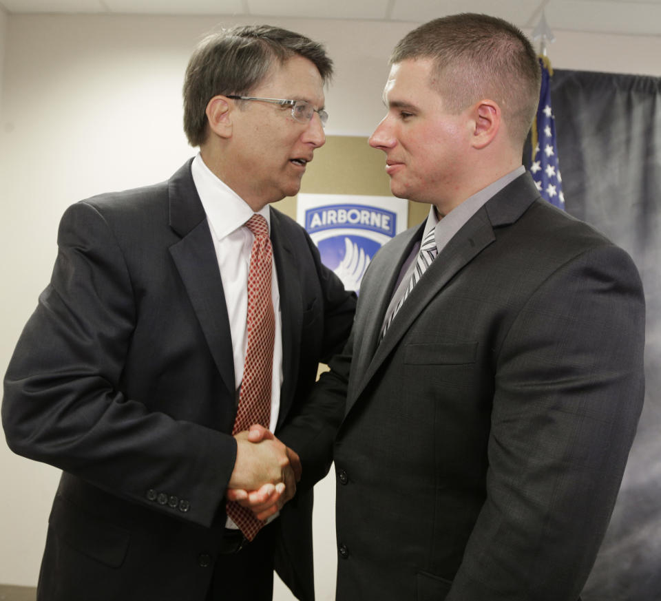 U.S. Army Specialist Kyle White, right, shakes hands with North Carolina Gov. Pat McCrory, left, after talking about his role during an ambush on his platoon in eastern Afghanistan that earned him the Medal of Honor during a news conference in Charlotte, N.C., Wednesday, April 23, 2014. (AP Photo/Chuck Burton)