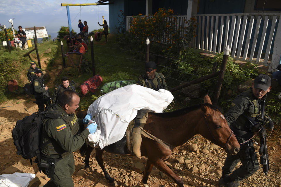 Police officers transport the body of one of at least five people killed during a skirmish between illegal armed groups in Jamundi, southwest Colombia, Friday, Jan. 17, 2020. Authorities say rebels with the former Revolutionary Armed Forces of Colombia operate in the area and may have been involved. (AP Photo/Christian EscobarMora)