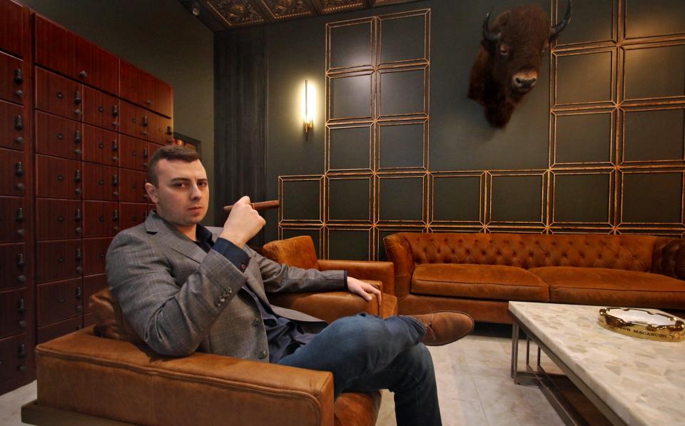 Owner Jacob Hibberts sits with a cigar in one of the many room of WhiskGars Cigar & Co. on West Main Ave. in Gastonia  Thursday morning, Jan. 20, 2022.