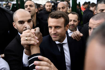 Emmanuel Macron (C), head of the political movement En Marche !, or Onwards !, and candidate for the 2017 presidential election, shakes hands with a youth during a campaign visit in Sarcelles, near Paris, April 27, 2017. REUTERS/Martin Bureau/Pool