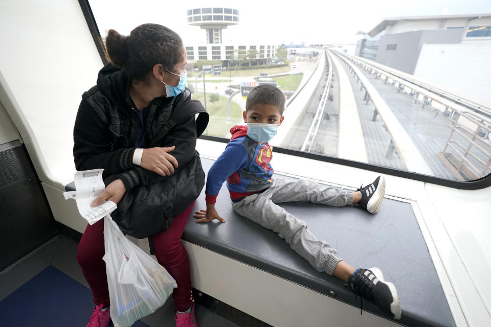 Yancarlos Amaya, 5, right, a migrant from Honduras, and his mother, Celestina Ramirez, ride a tram between terminals during a layover at George Bush International Airport, Wednesday, March 24, 2021, in Houston. A few days ago, Yancarlos was walking along a muddy river bank after crossing the Rio Grande and landing on the U.S. side of the border with Mexico. Ramirez said they turned themselves in to U.S. Border Patrol officers and later spent hours in custody, a night under a bridge and three more days in a detention facility. (AP Photo/Julio Cortez)