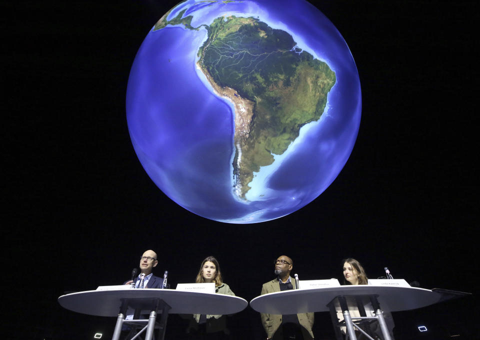 FILE - Niklas Hoehne, from left, New Climate Institute Cologne, Luisa Neubauer, Fridays for Future activist, Peter Donatus, journalist and activist, and Linda Kastrop, activist, stand in front of a giant globe in the exhibition "The Fragile Paradise" during a news conference on planned actions in 2022 and discuss "greenwashing" in Brussels, Oberhausen, Germany, Feb. 11, 2022. The U.S. has renewed legitimacy on global climate issues and will be able to inspire other nations in their own emissions-reducing efforts, experts said, after the Democrats pushed their big economic bill through the Senate on Sunday, Aug. 7, 2022. Climate activists agree that the bill is just one step on a larger path towards climate action. (Roland Weihrauch/dpa via AP, File)