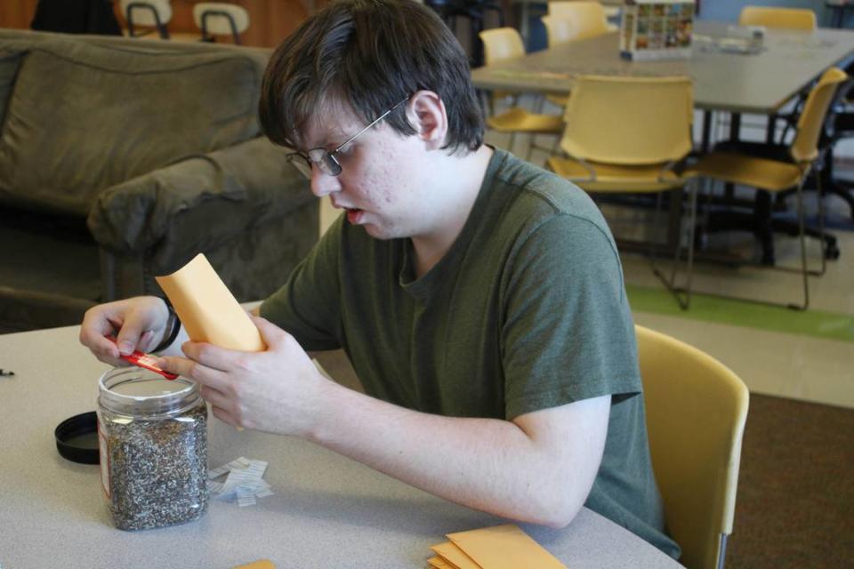 Kyle Allison, 19, scoops some of the smaller seeds into an envelope. The seed packets are part of a new venture involving Spring Hill High School and the Gifted Learning Project.