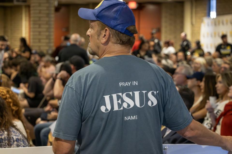  A man wears an evangelical t-shirt and holds a banner in support of a policy that the Chino Valley school board is meeting to vote on which would require school staff to \"out\" students to their parents.