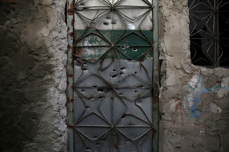 The front door of an abandoned house which is damaged by bullet holes, is seen in a passage known as "beco da Siria" (Syria alley) in Jacarezinho slum in Rio de Janeiro, Brazil, January 10, 2018. REUTERS/Pilar Olivares