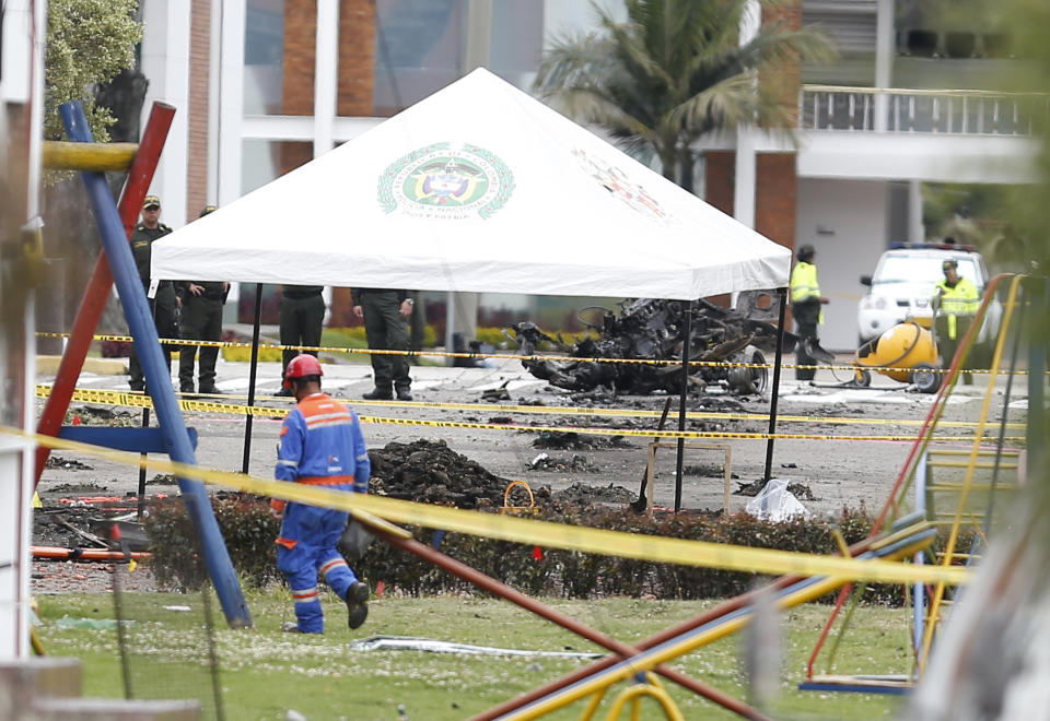 Police investigate the remains a a car bomb at the General Francisco de Paula Santander Police Academy after an attack, in Bogota, Colombia, Friday, Jan. 18, 2019. Colombia blames the National Liberation Army, ELN, rebels for the deadly attack that left more than 20 dead and wounded many others. (AP Photo/John Wilson Vizcaino)