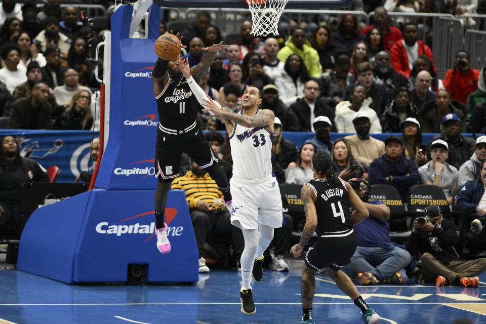 Washington Wizards forward Kyle Kuzma (33) goes to the basket against Los Angeles Clippers guard John Wall (11) and guard Brandon Boston Jr. (4) during the first half of an NBA basketball game, Saturday, Dec. 10, 2022, in Washington. (AP Photo/Nick Wass)