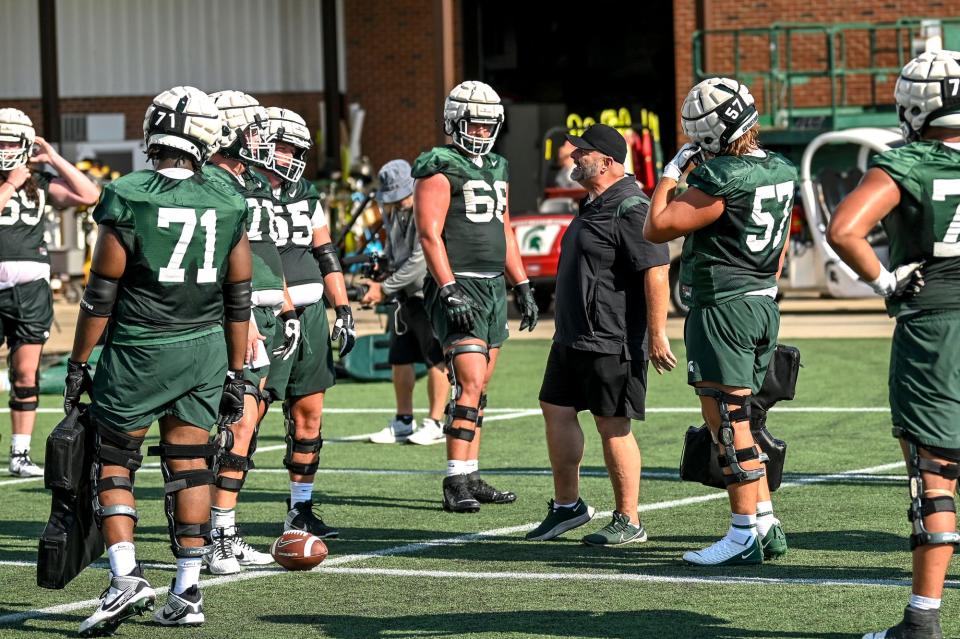 Michigan State's offensive line coach Chris Kapilovic, center, talks with players during the opening day of MSU's football fall camp on Thursday, Aug. 3, 2023, in East Lansing.