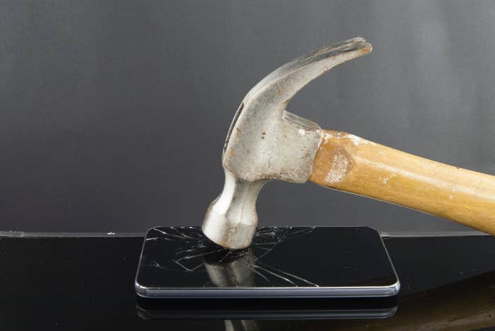 A hammer breaking the screen of a smartphone