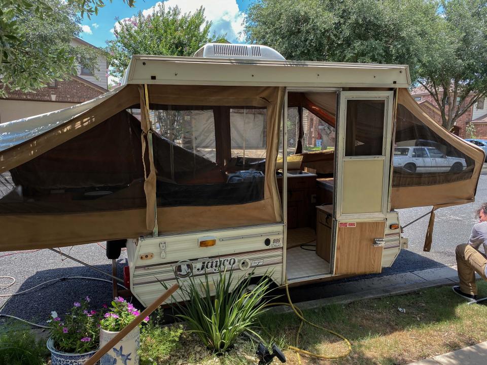 An old camper with a white exterior with brown clothe before renovations