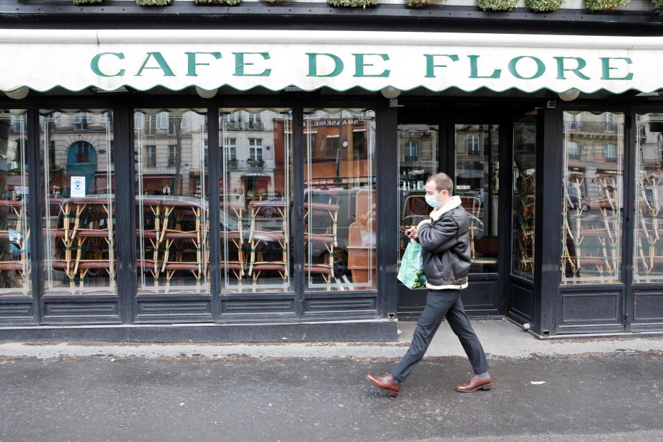 A man wearing a protective face mask walks past famous Cafe de Flore closed along with all cafes and restaurants to curb the spread of the coronavirus, Covid-19, in the Saint-Germain-des-Prés district of Paris on March 15, 2021. (Photo by Ludovic MARIN / AFP) (Photo by LUDOVIC MARIN/AFP via Getty Images)
