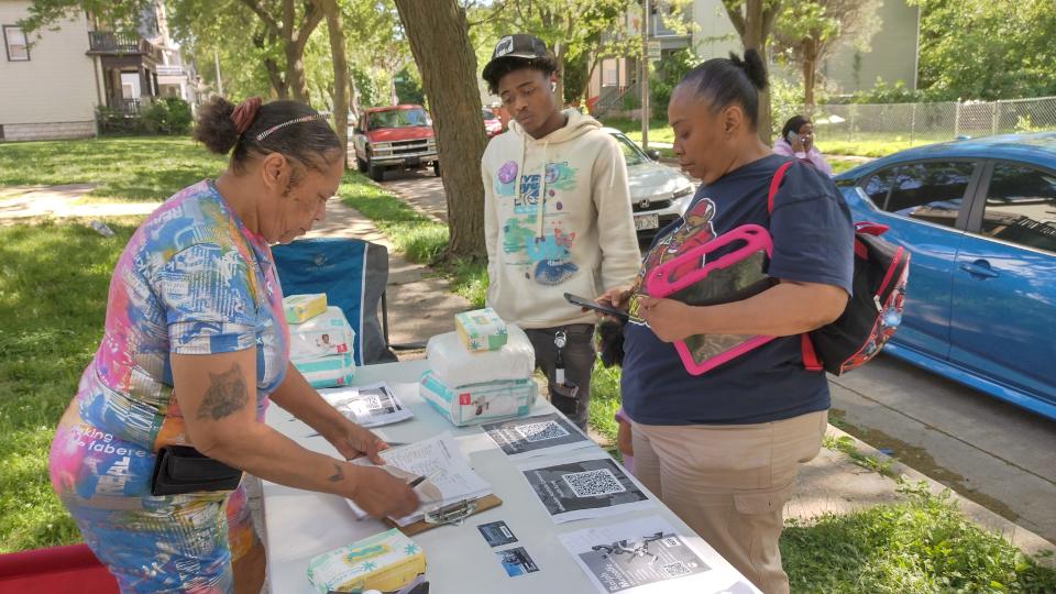 Patrice Gransberry (left), a volunteer with Metcalfe Park Community Bridges mutual aid shed, distributes information to Zemarius Jones and Johnnie Mae Ashford on social and free cultural services they can use.