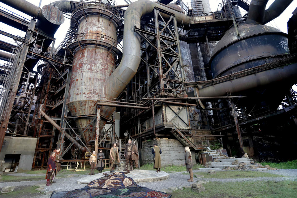 In this Saturday, May 18, 2019, photo actor Jeffrey Carpenter, center, portraying the character King Lear looks over a large quilted cape that depicts his kingdom as he performs in the opening of the Quantum Theatre production of Shakespeare's tragedy at the site of the old Carrie steel producing blast furnace in Swissvale, Pa. (AP Photo/Keith Srakocic)