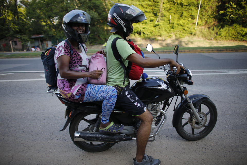 In this Sept. 2, 2018 photo, Venezuelan Sandra Cadiz gets a free ride from a motorcyclist to Peroles, Colombia, on her journey to Peru. The driver then returned for her 10-year-old daughter. Nine days and nearly two thousand miles after fleeing Caracas, Cadiz and her 10-year-old daughter reached the final border they'd set out to cross. (AP Photo/Ariana Cubillos)