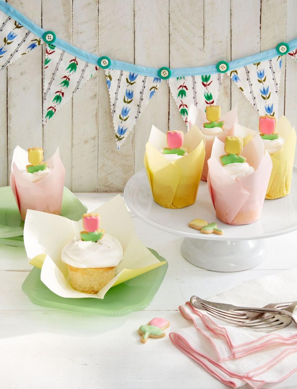 tulip cupcakes in yellow and pink pastel paper liners with small tulip shaped sugar cookies on top as garnish