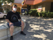 Ron Starkey waits for a bus in Yuba City, Calif., Thursday, July 9, 2020. Sutter County was one of the first counties to reopen its economy when it defied Gov. Gavin Newsom's stay-at-home order in May to allow restaurants, hair salons, gyms and shopping malls to reopen. But Thursday, the county was added to a state watch list because of its rising number of coronavirus cases and hospitalizations. That will eventually trigger another round of restrictions, forcing bars to close and indoor operations to cease at restaurants and other public places for three weeks. Starkey said he was frustrated with the closings. "I think this is all a hoax," he said. (AP Photo/Adam Beam)