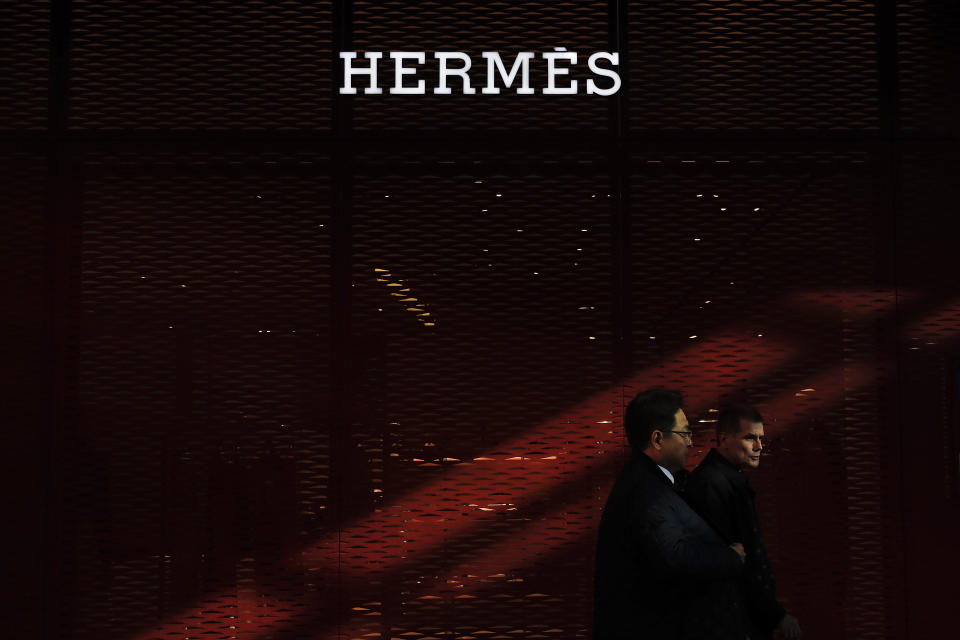 A Chinese and foreign businessmen walk by an Hermes flagship store at the Central Business District in Beijing, Wednesday, March 6, 2019. China will bar government authorities from demanding overseas companies hand over technology secrets in exchange for market share, a top economic official said Wednesday, addressing a key complaint at the heart of the current China-U.S. trade dispute. (AP Photo/Andy Wong)