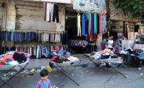 Clothing for sale is displayed along a street in the city of Idlib